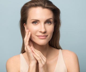 Woman with smooth, youthful skin touching her face after Thermage treatment