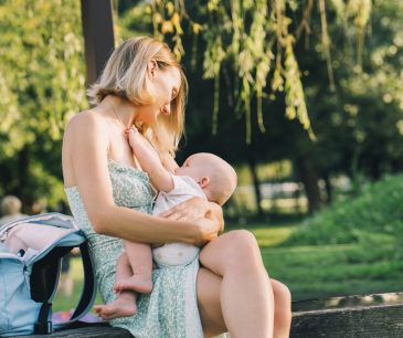 Mother breastfeeding her baby on a park bench, illustrating natural nipple changes after nursing