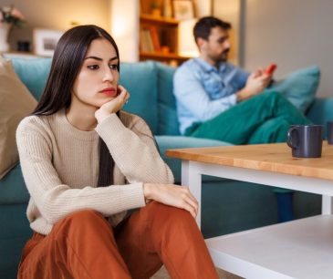 Woman with a neutral expression sitting at home, illustrating the concept of resting angry face (RBF) and how it can be softened with Botox and fillers at ICLS.