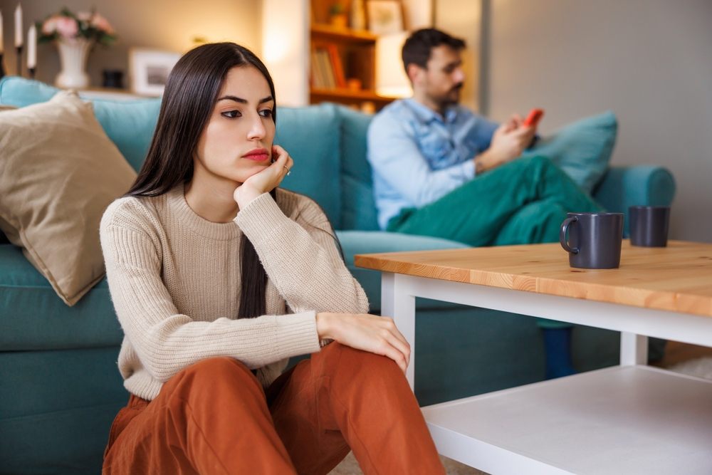 Woman with a neutral expression sitting at home, illustrating the concept of resting angry face (RBF) and how it can be softened with Botox and fillers at ICLS.