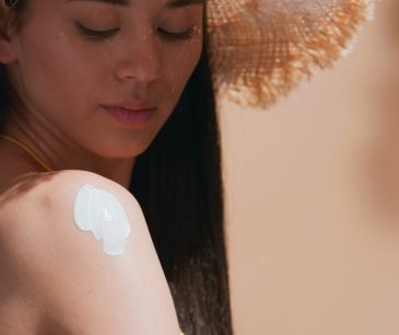 Woman applying sunscreen on shoulder to prevent summer sunburn and protect skin