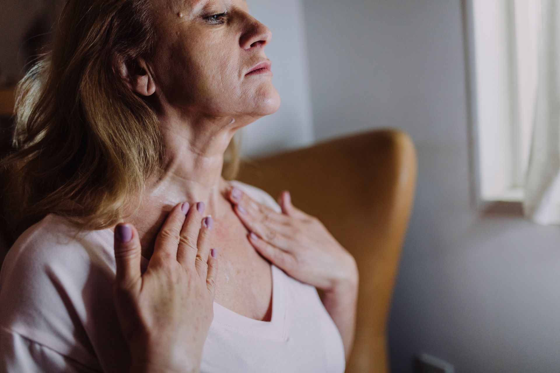 mature woman gently massaging moisturizer into her neck
