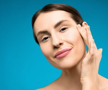 woman touching bare face and smiling