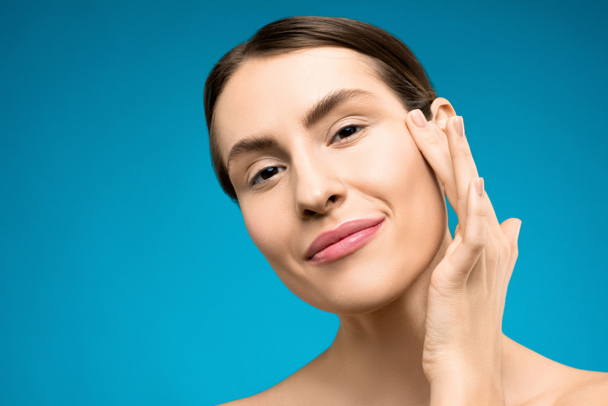 woman touching bare face and smiling